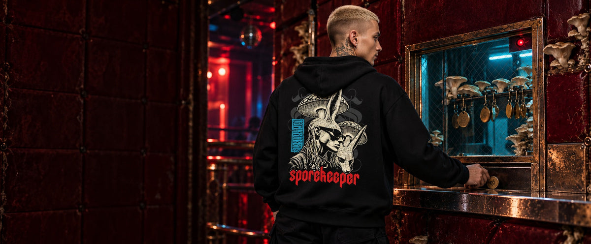 James wearing the black Spore Keeper hoodie at a fungal nightclub admission hatch.