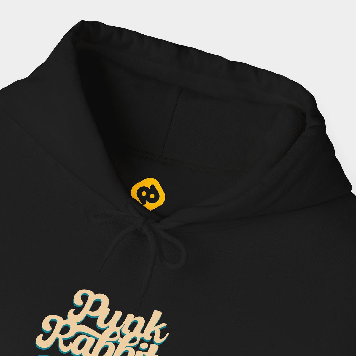 Doctor Dolly black hoodie neckline and chest close-up showing cream Punk Rabbits script above a teal banner and small red ornament and yellow neck branding.