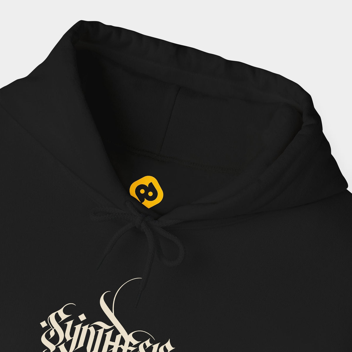 Opsis black hoodie neckline and chest close-up showing black drawstrings, the inner yellow brand mark and ivory Synthesis lettering.