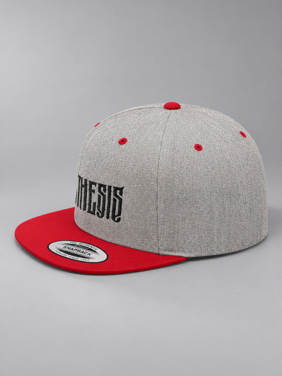 Synthesis Blackout snapback in Heather Grey/Red, three-quarter view showing angular black Synthesis embroidery and flat bill on gray.