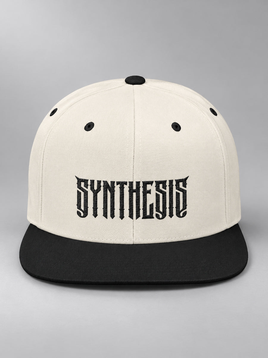 Synthesis Blackout snapback in Natural/Black, front view showing black angular Synthesis embroidery and flat bill on gray.