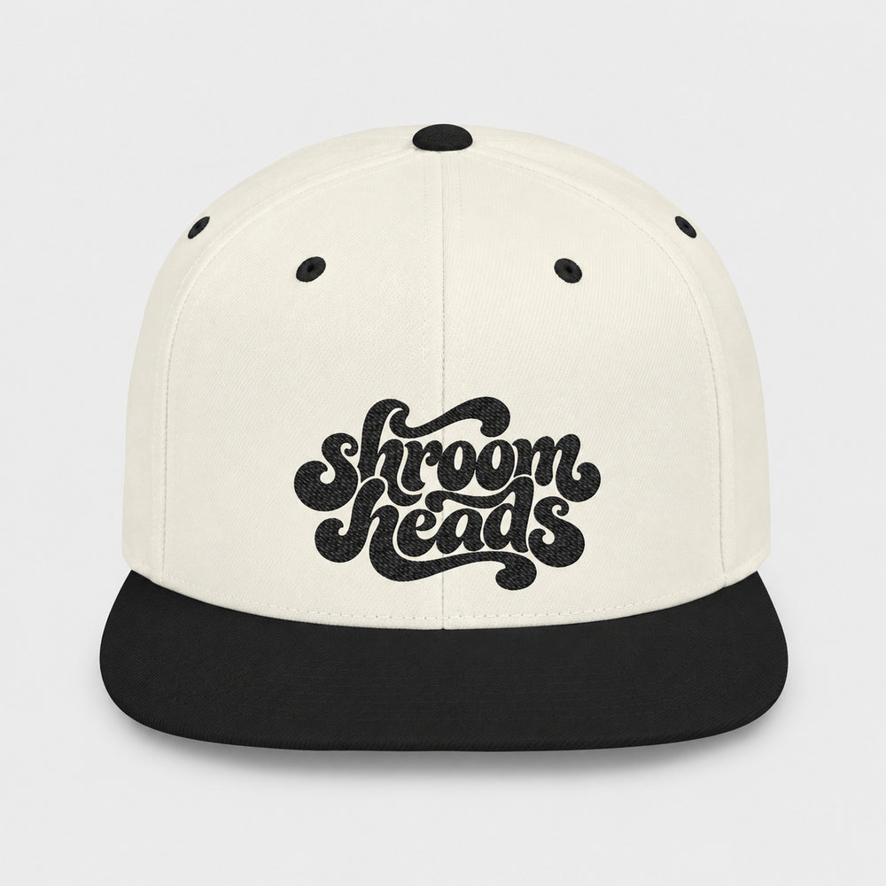 Natural crown and black flat bill snapback with black Shroom Heads script embroidery on light gray.