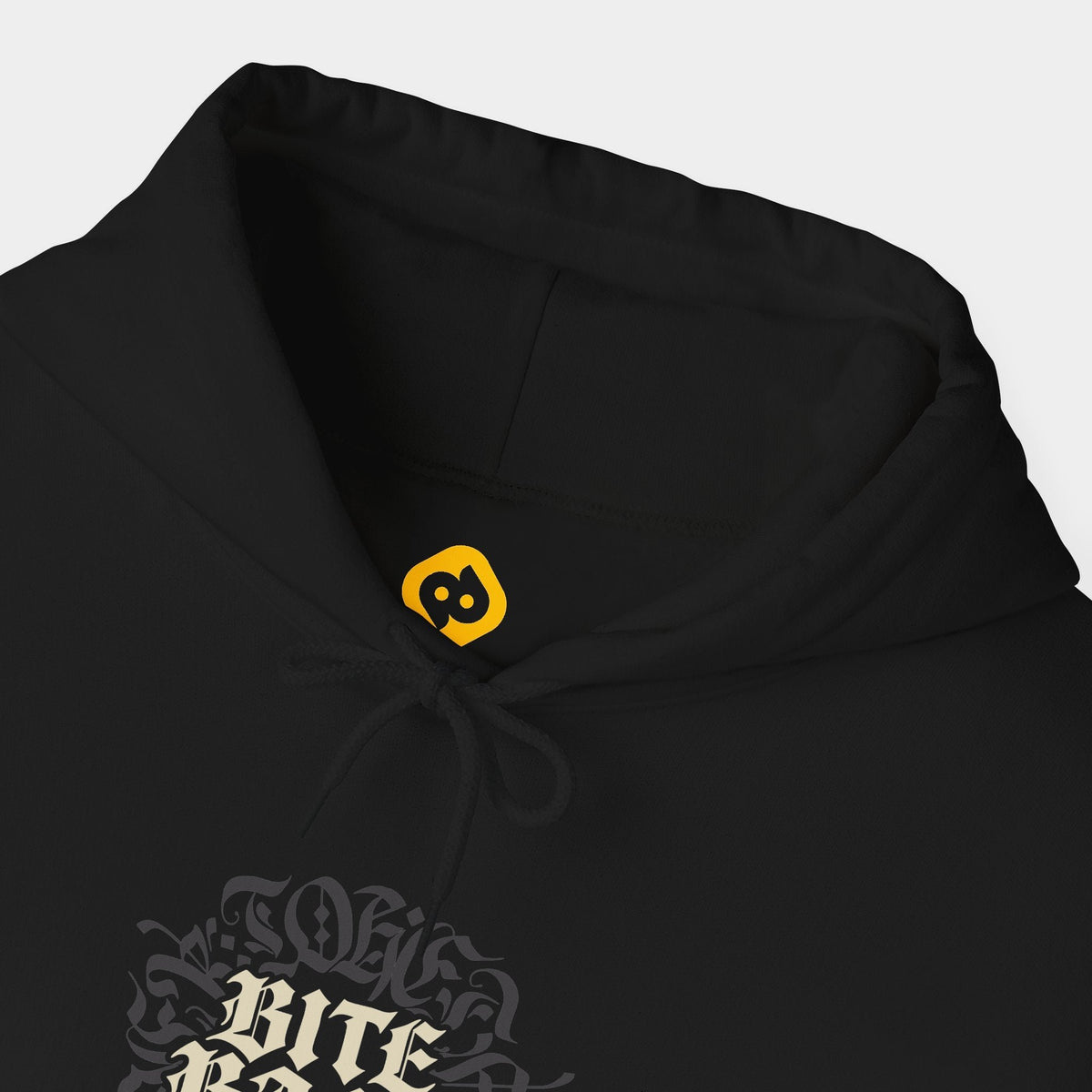 Bite Back black hoodie neckline and chest close-up showing cream Bite Back blackletter in two stacked lines over a dark charcoal ornamental circle.
