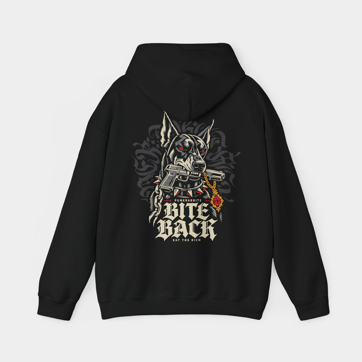 Bite Back black hoodie, back view showing a Doberman with red eyes and a spiked collar, gripping an illustrated handgun, beside a gold chain and red pendant; Punkrabbits, Bite Back and Eat the Rich lettering complete the composition.