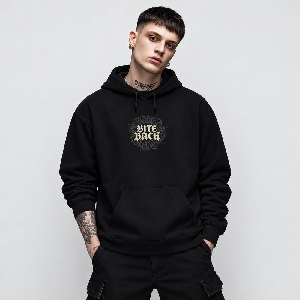 Nico wearing the black Bite Back hoodie, front view showing cream Bite Back blackletter in two stacked lines over a dark charcoal ornamental circle.