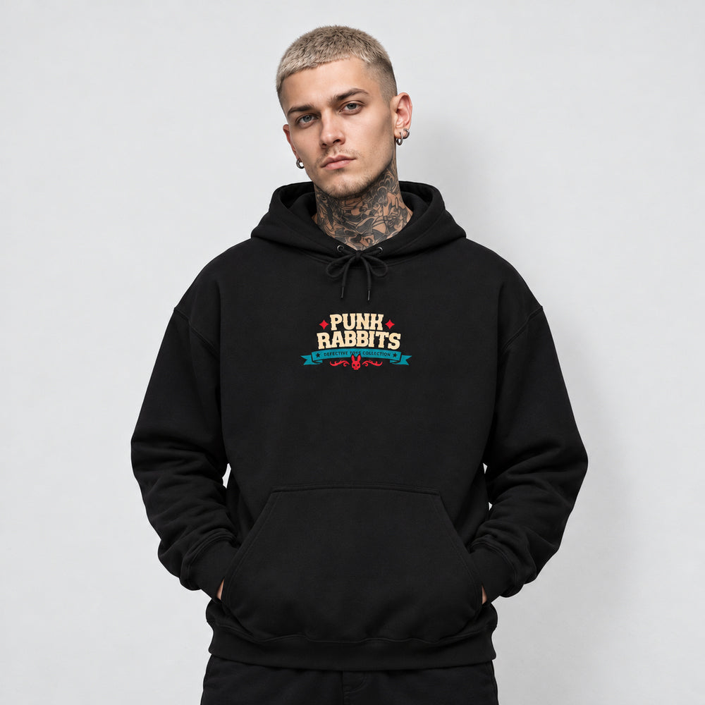 James wearing the black Cannibal Ted hoodie, front view showing compact cream PUNK RABBITS lettering with red stars, a teal Defective Toys Collection banner and red ornament.