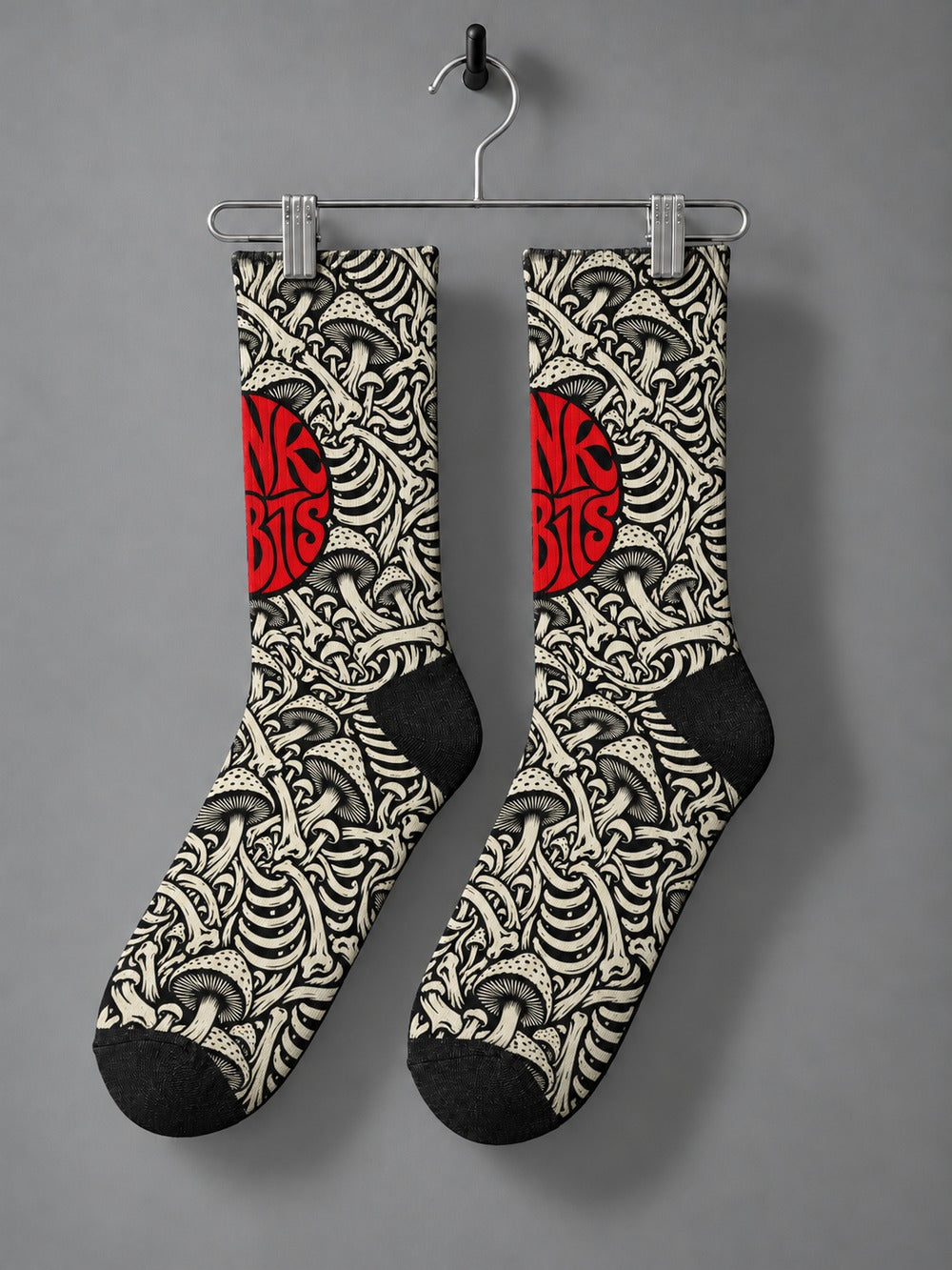Pair hanging from a chrome clip hanger: black crew socks with ivory mushroom and skeletal artwork and a red circular Punkrabbits logo.