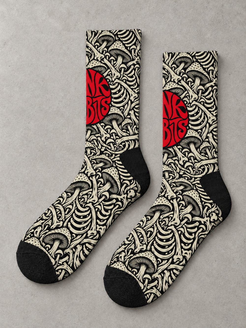 Overhead flat-lay pair in side profile: black crew socks with ivory mushroom and skeletal artwork and a red circular Punkrabbits logo.