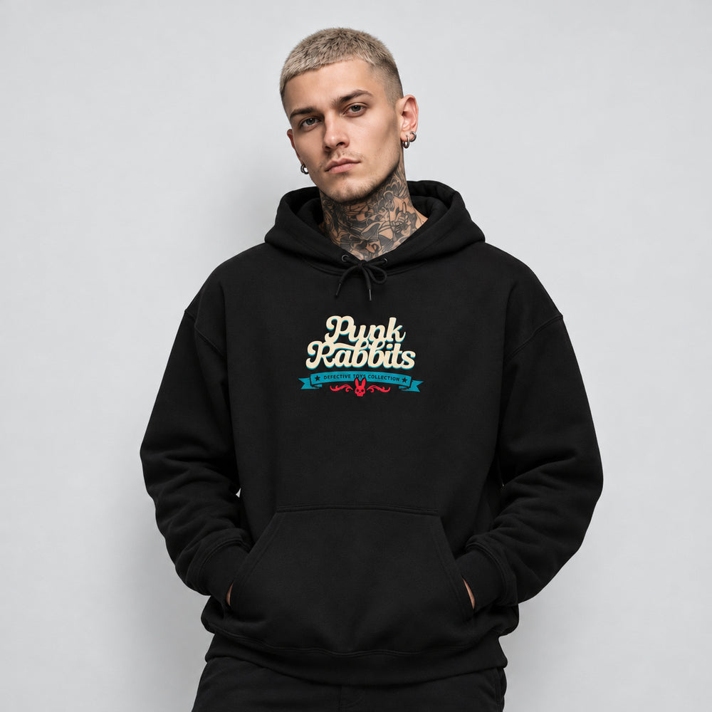 James wearing the black Doctor Dolly hoodie, front view showing cream Punk Rabbits script above a teal banner and small red ornament.