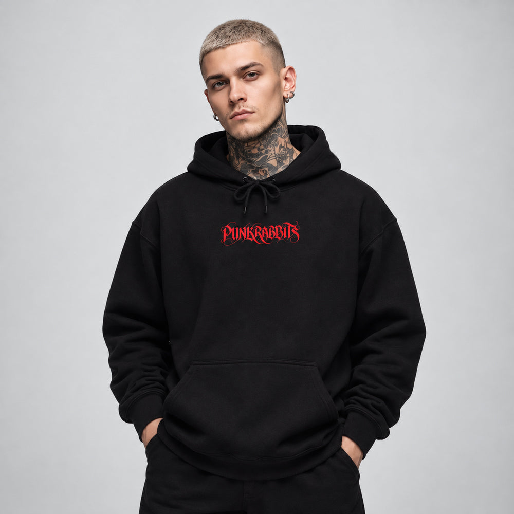 James wearing the black Ecstasis hoodie, front view showing a compact red Punkrabbits calligraphic wordmark.