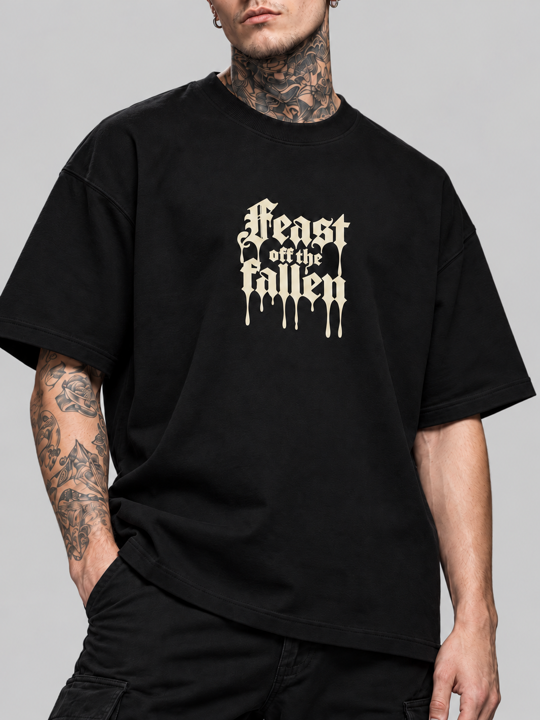 Close-up of black Feast off the fallen Premium Boxy Tee on James, showing crew neckline, cotton fabric and ivory blackletter chest print.