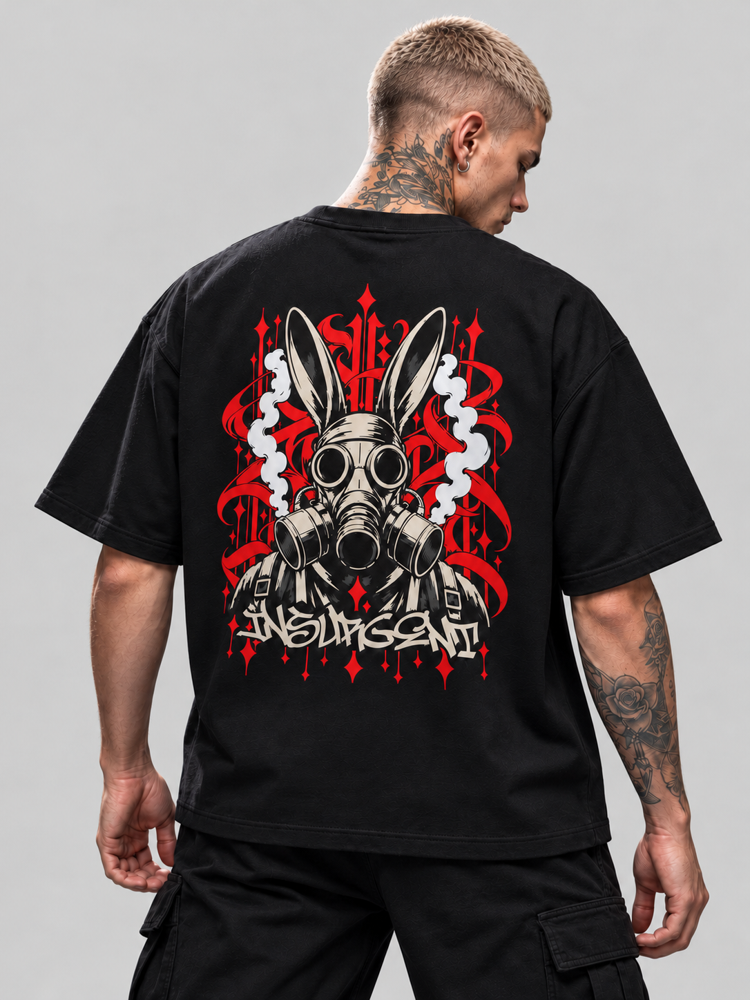 Close-up of black Insurgent Premium Boxy Tee back artwork, rabbit-eared gas mask, pale smoke and red ornament on James.