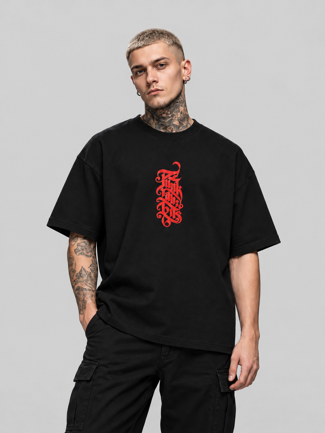 James wearing black Insurgent Premium Boxy Tee, front view with vertical red Punkrabbits chest lettering in a gray studio.