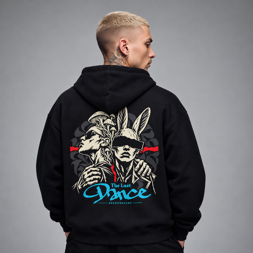James wearing the black Last Dance hoodie, back view showing two linked figures, one mushroom-crowned and one rabbit-eared, with a red band and blue The Last Dance script.