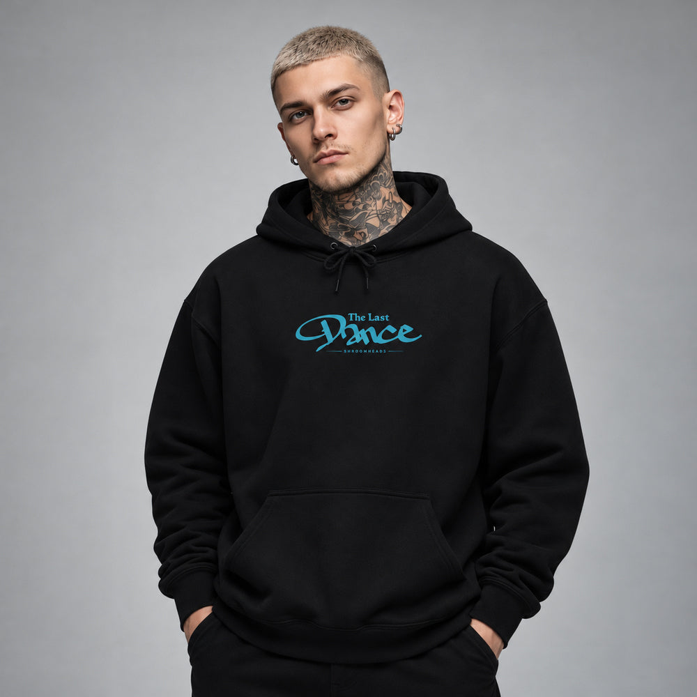 James wearing the black Last Dance hoodie, front view showing blue The Last Dance script with small Shroomheads lettering.