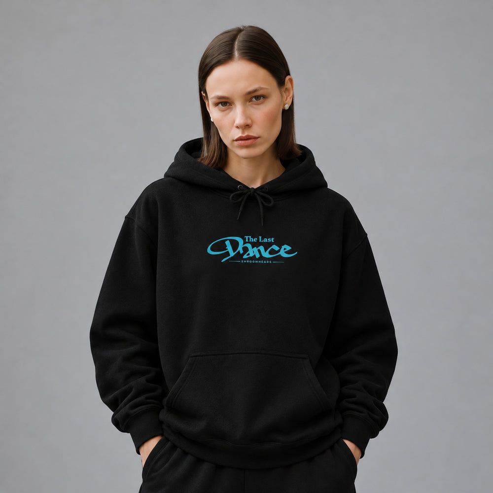 Mara wearing the black Last Dance hoodie, front view showing blue The Last Dance script with small Shroomheads lettering.