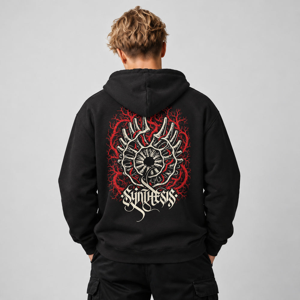 Theo wearing the black Opsis hoodie, back view showing the ivory eye-like emblem, red branching network and ivory Synthesis lettering.