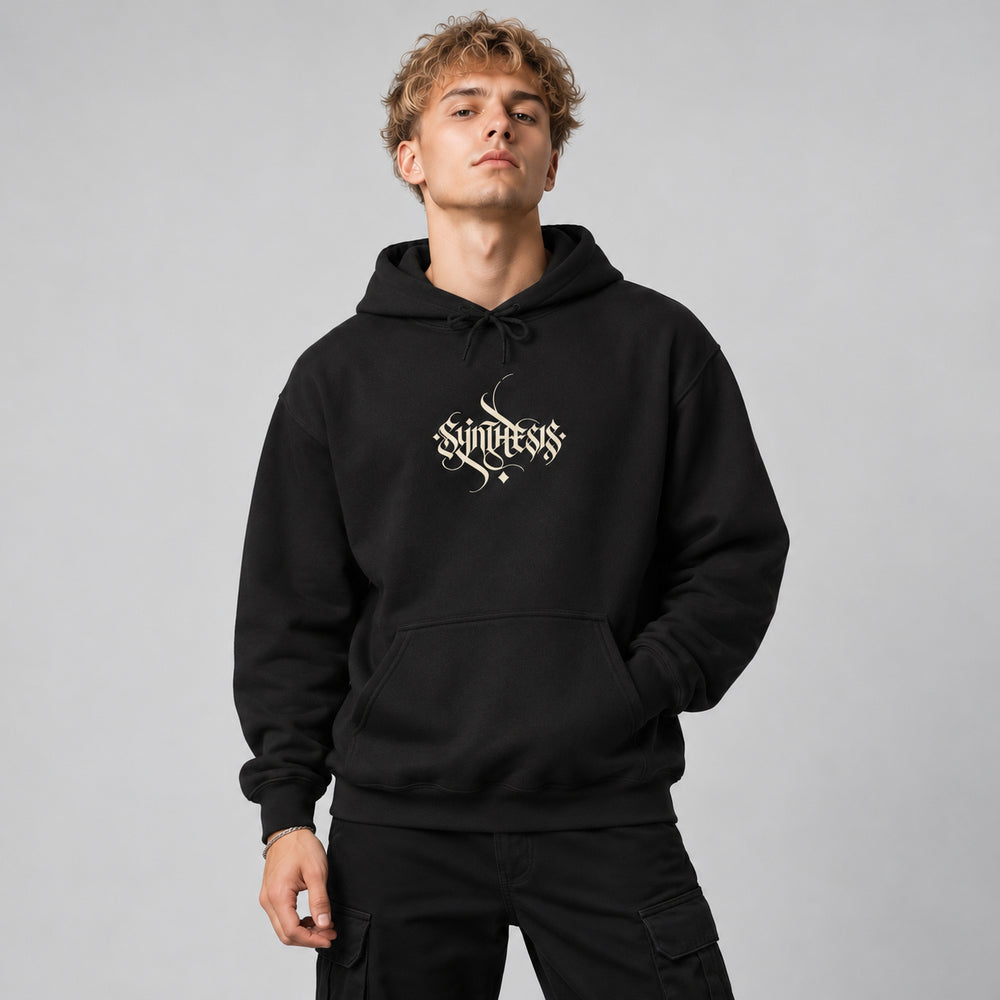 Theo wearing the black Opsis hoodie, front view showing small ivory Synthesis calligraphic chest lettering.