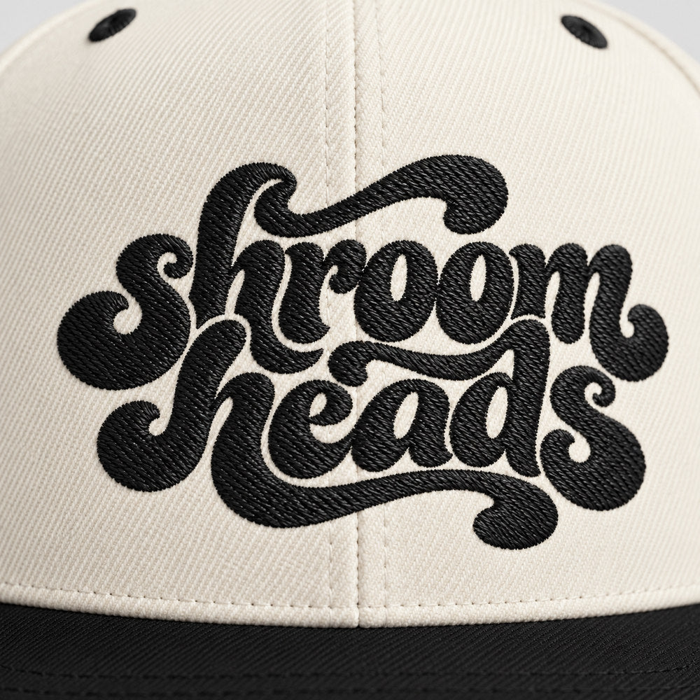 Close-up of black Shroom Heads script embroidery on the Natural/Black snapback.