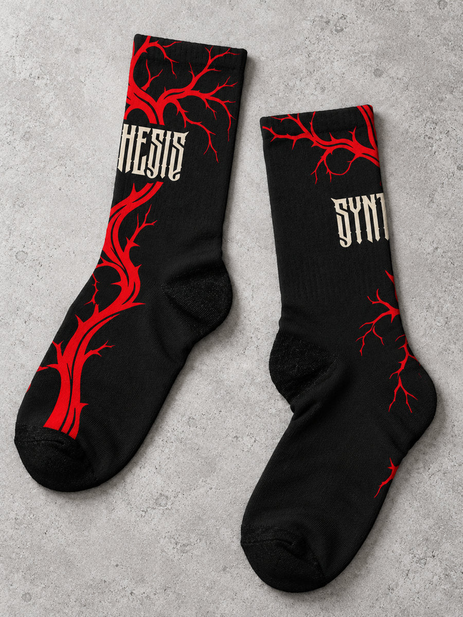 Bleeding Tree Synthesis crew sock pair arranged diagonally on gray concrete, showing dense and sparse red branches and wrapped ivory lettering.
