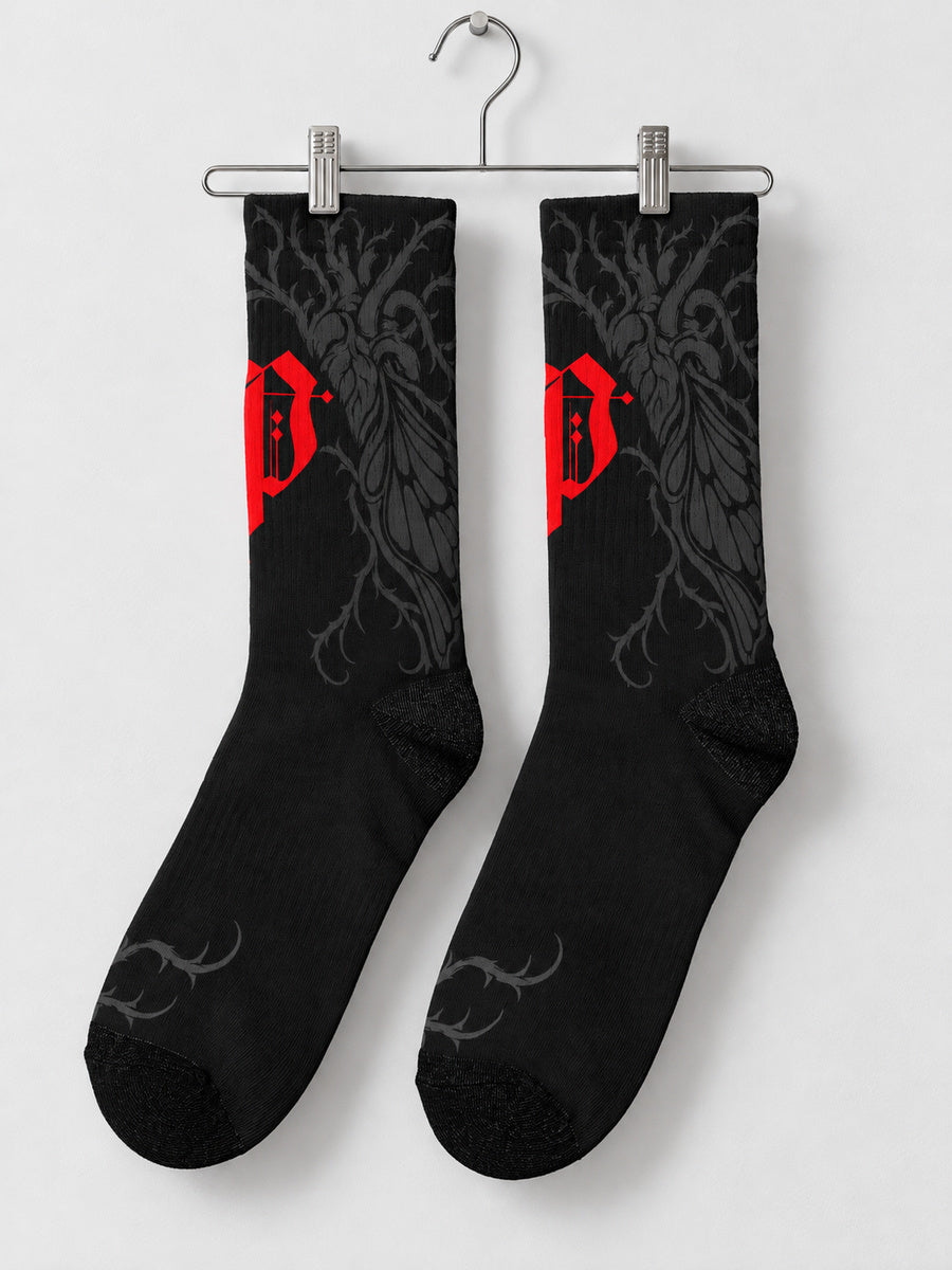 Synthesis Butterfly Roots socks — pair on metal clip hanger, outer patterned view, black with red Gothic P and dark gray butterfly roots.