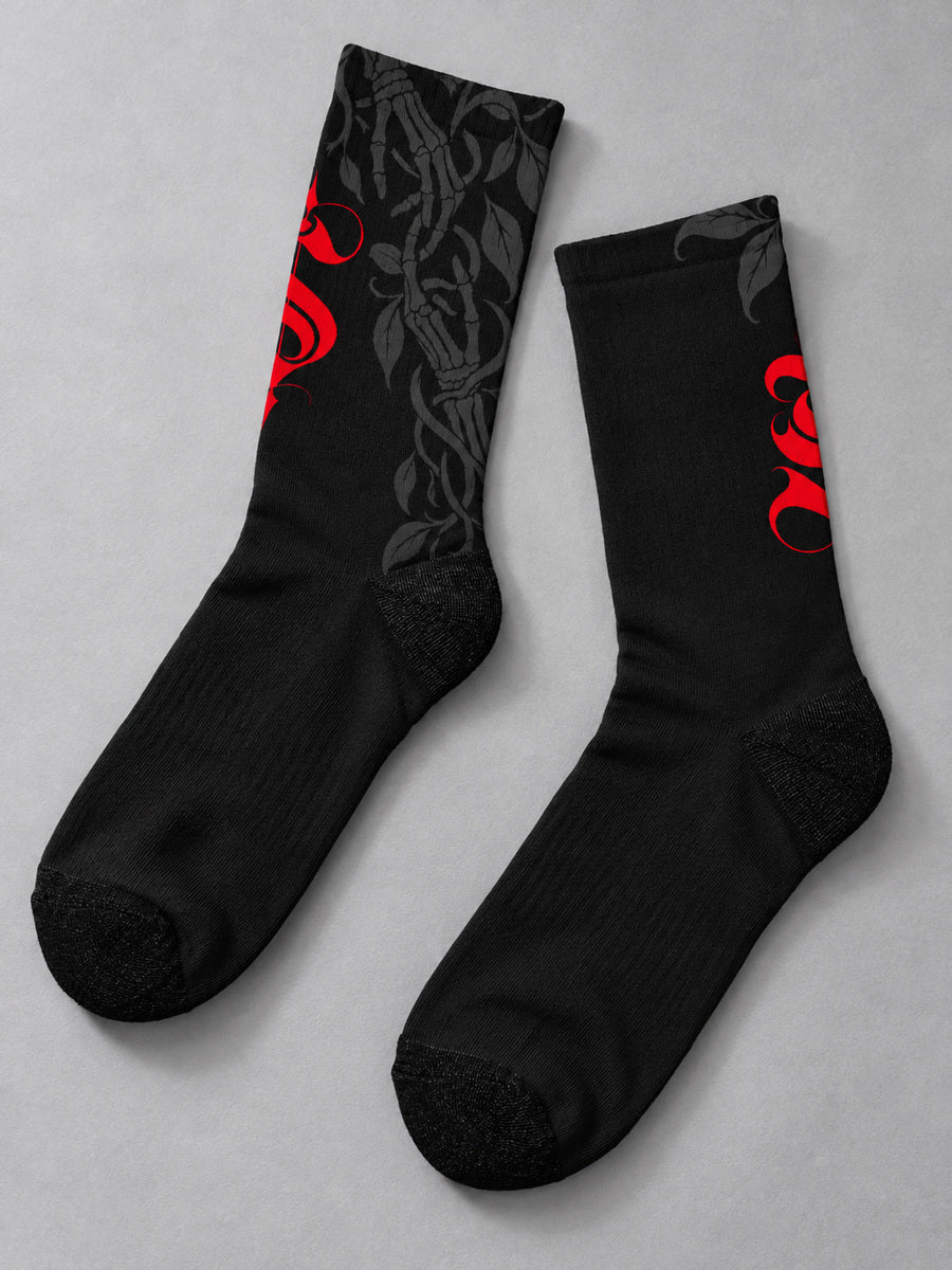 Synthesis Death Grip socks — styled pair flat lay, both verified printed views, black with red ornate S and dark gray skeletal hands with leaves.
