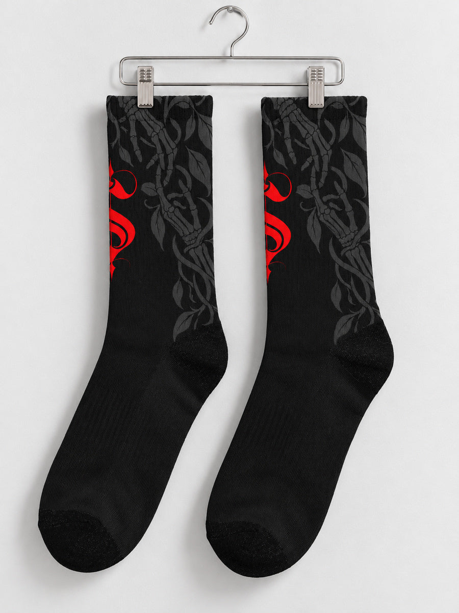 Synthesis Death Grip socks — pair on metal clip hanger, outer patterned view, black with red ornate S and dark gray skeletal hands with leaves.