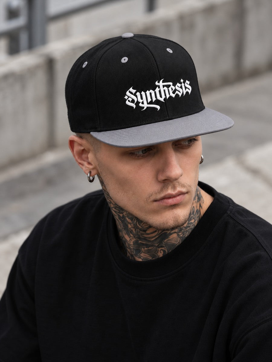 James wearing the Black/Silver Synthesis Doomed snapback low at the temples, with the flat silver bill and white Gothic embroidery visible.