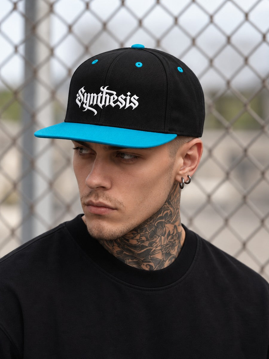 James wearing the Black/Teal Synthesis Doomed snapback, looking off to the left with the flat teal bill and white Gothic embroidery visible.