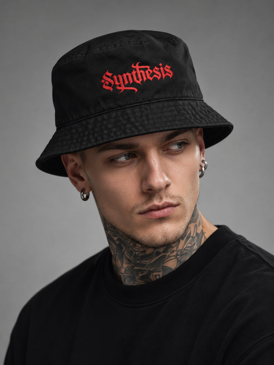 James looking off-camera in a turned studio portrait wearing the black Synthesis Red Ritual bucket hat.