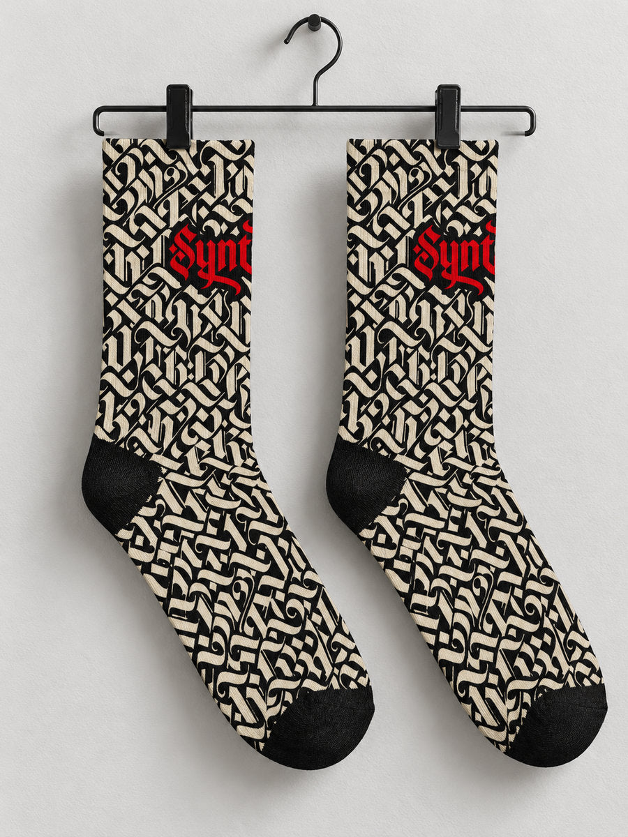 Synthesis script sock pair hanging from black metal clips, opposite printed view.