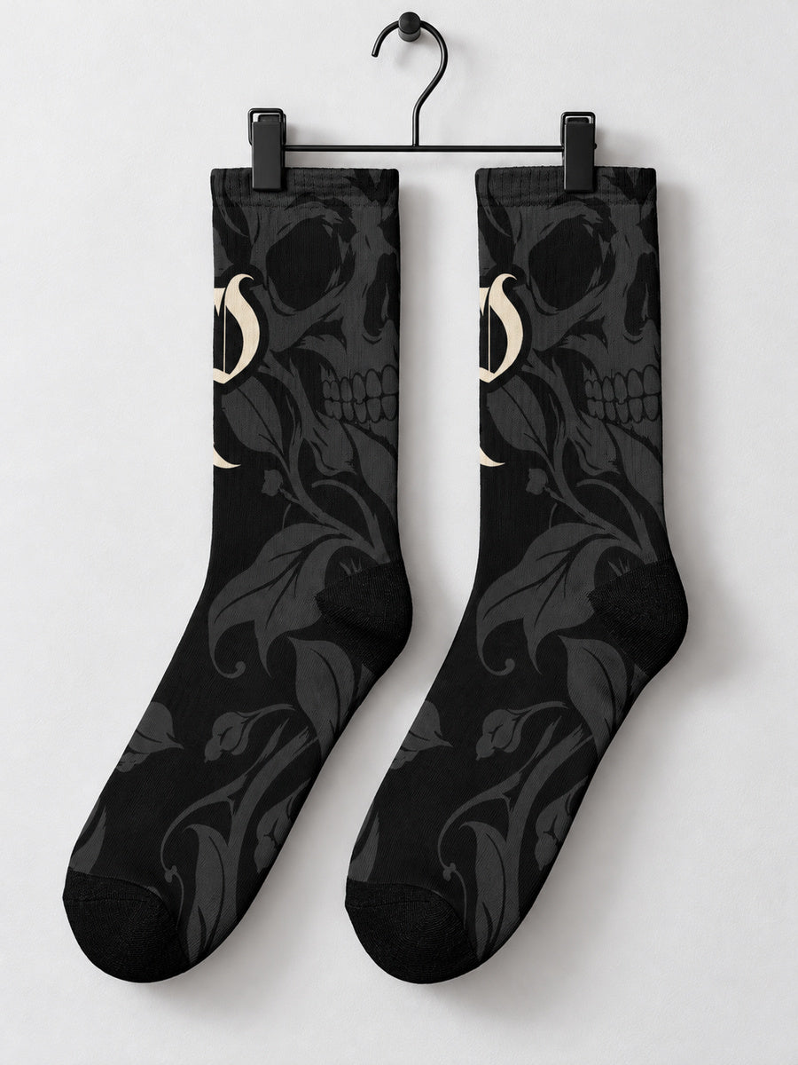 Synthesis skull bloom sock pair hanging from black metal clips, skull-facing view.