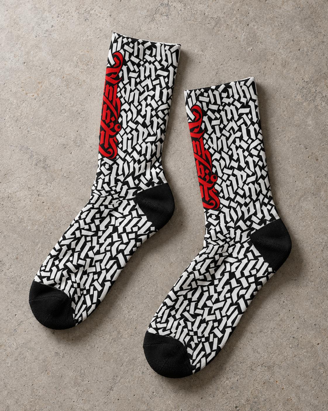 Punkrabbits Red Script crew socks laid flat on concrete, showing black toes and heels