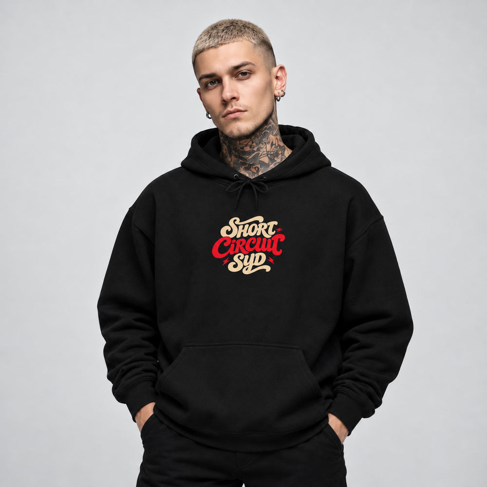 James wearing the black Short Circuit Syd hoodie, front view showing stacked cream and red Short Circuit Syd script centered on the chest.