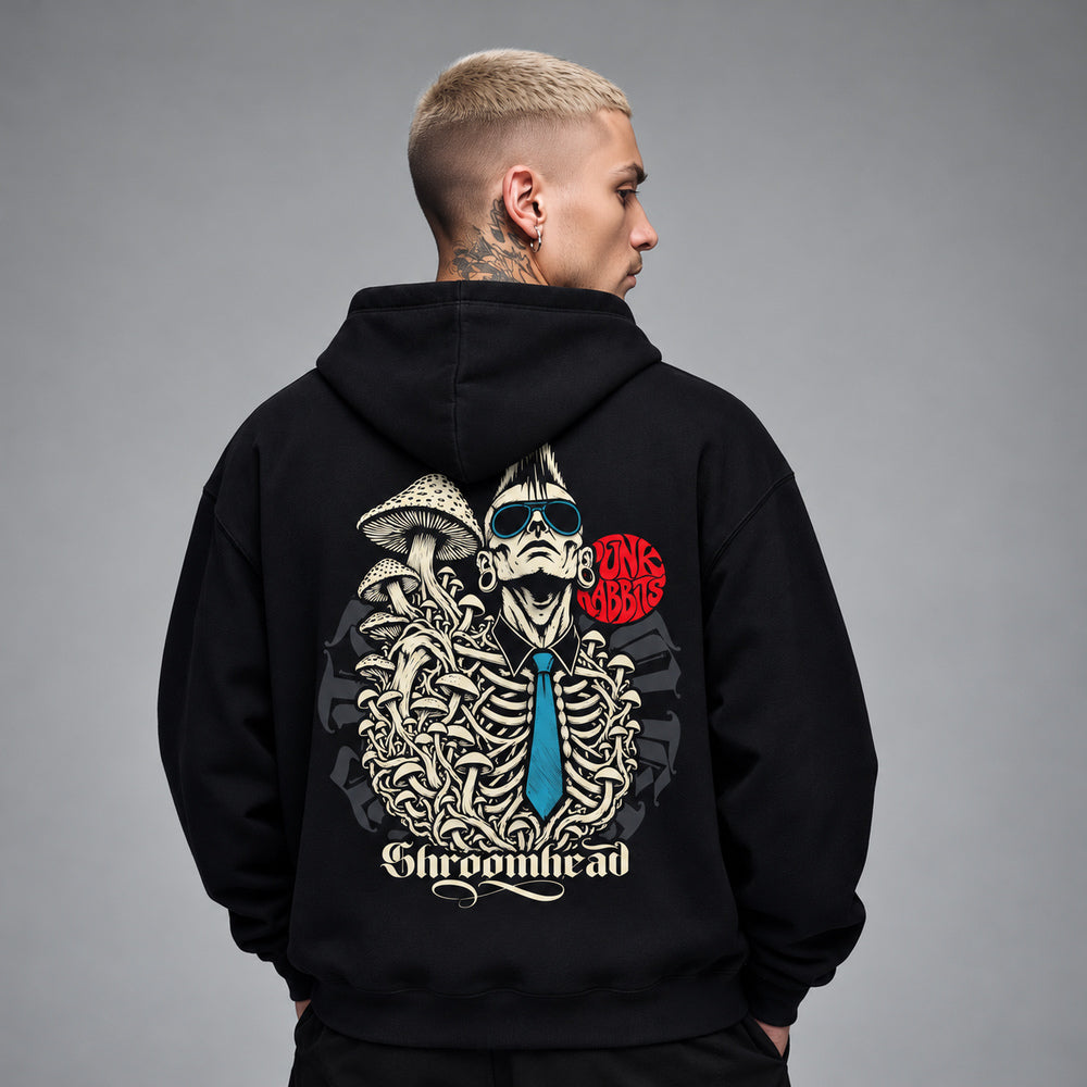 James wearing the black Shroomhead hoodie, back view showing a mohawked figure in sunglasses with an exposed ribcage, mushrooms and a blue tie beneath a red Punkrabbits mark.