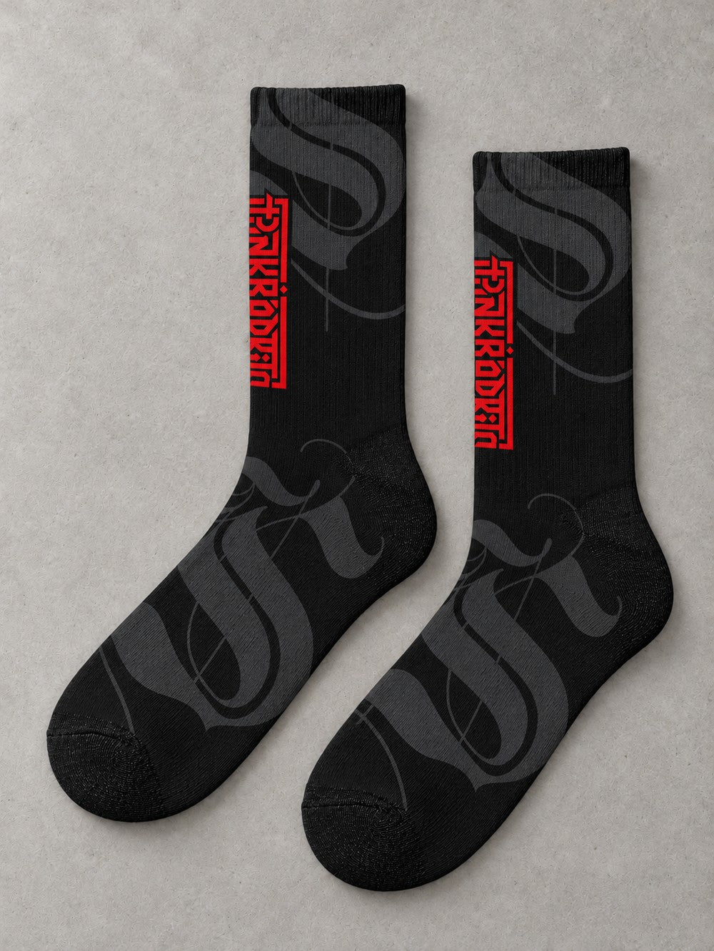 Overhead flat-lay pair in side profile: black crew socks with charcoal calligraphic strokes and a vertical red Punkrabbits wordmark.
