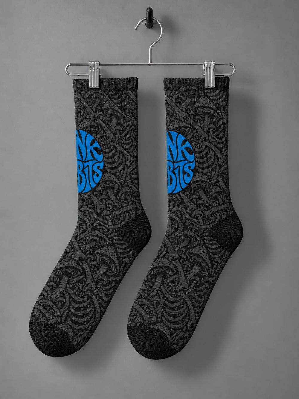 Pair hanging from a chrome clip hanger: black crew socks with charcoal mushroom and skeletal artwork and a blue circular Punkrabbits logo.