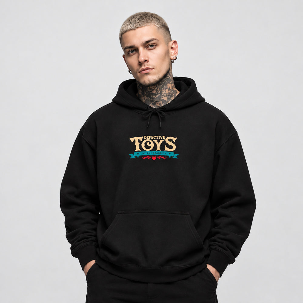 James wearing the black Sinister Sussie hoodie, front view showing cream Defective Toys lettering above a teal Punkrabbits banner and a small red flourish.