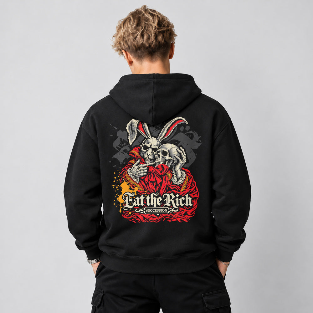 Theo wearing the black Succession hoodie, back view showing an ivory skeletal rabbit in a red ceremonial robe holding a human skull, with gold details, cream Eat the Rich lettering and the smaller Succession title.
