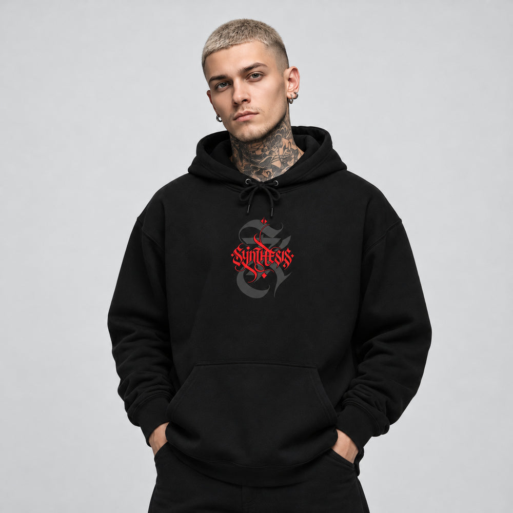 James wearing the black Synthesis hoodie, front view showing red Synthesis blackletter lettering over a charcoal ornamental S.