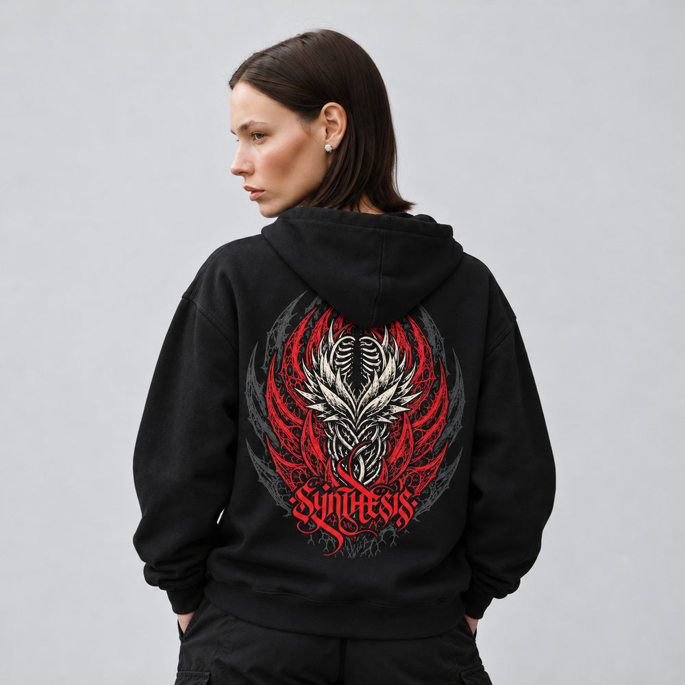 Mara wearing the black Synthesis hoodie, back view showing an ivory ribcage and interwoven organic forms framed by red thorn-like curves and charcoal ornament, with red Synthesis lettering.