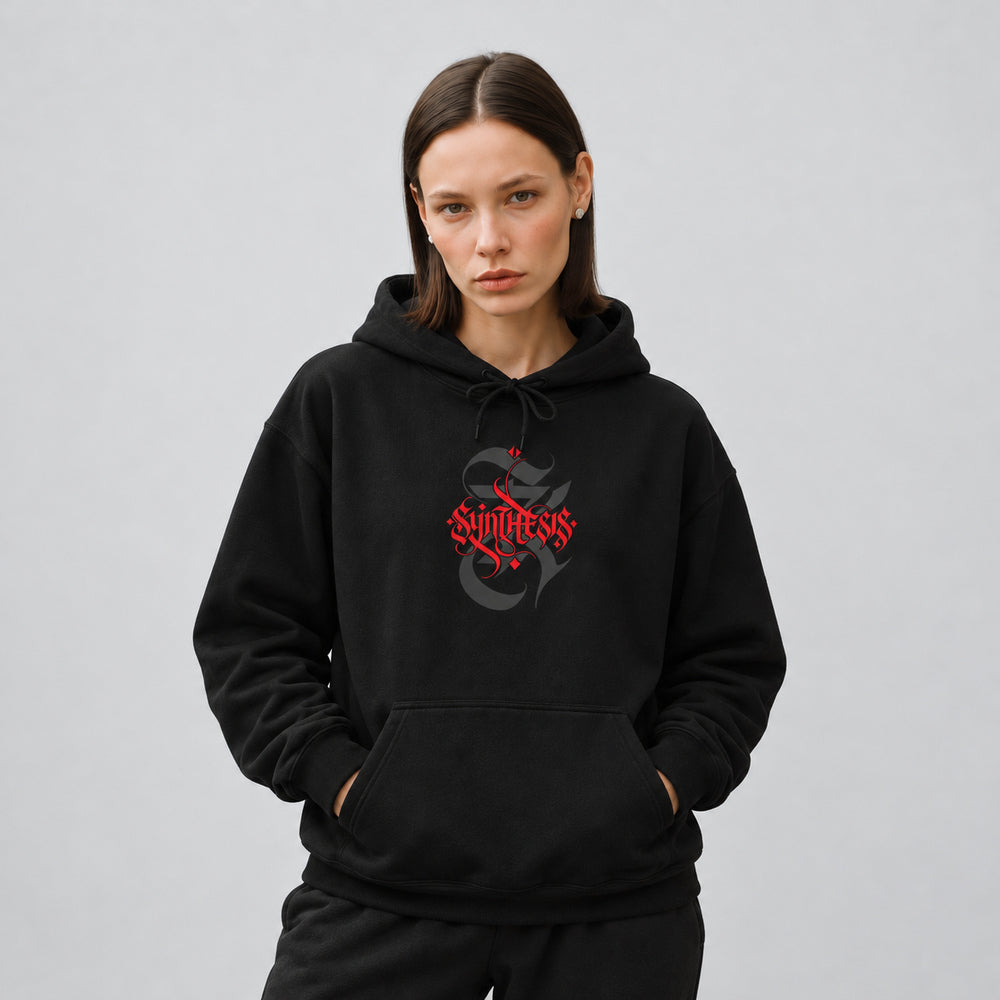 Mara wearing the black Synthesis hoodie, front view showing red Synthesis blackletter lettering over a charcoal ornamental S.