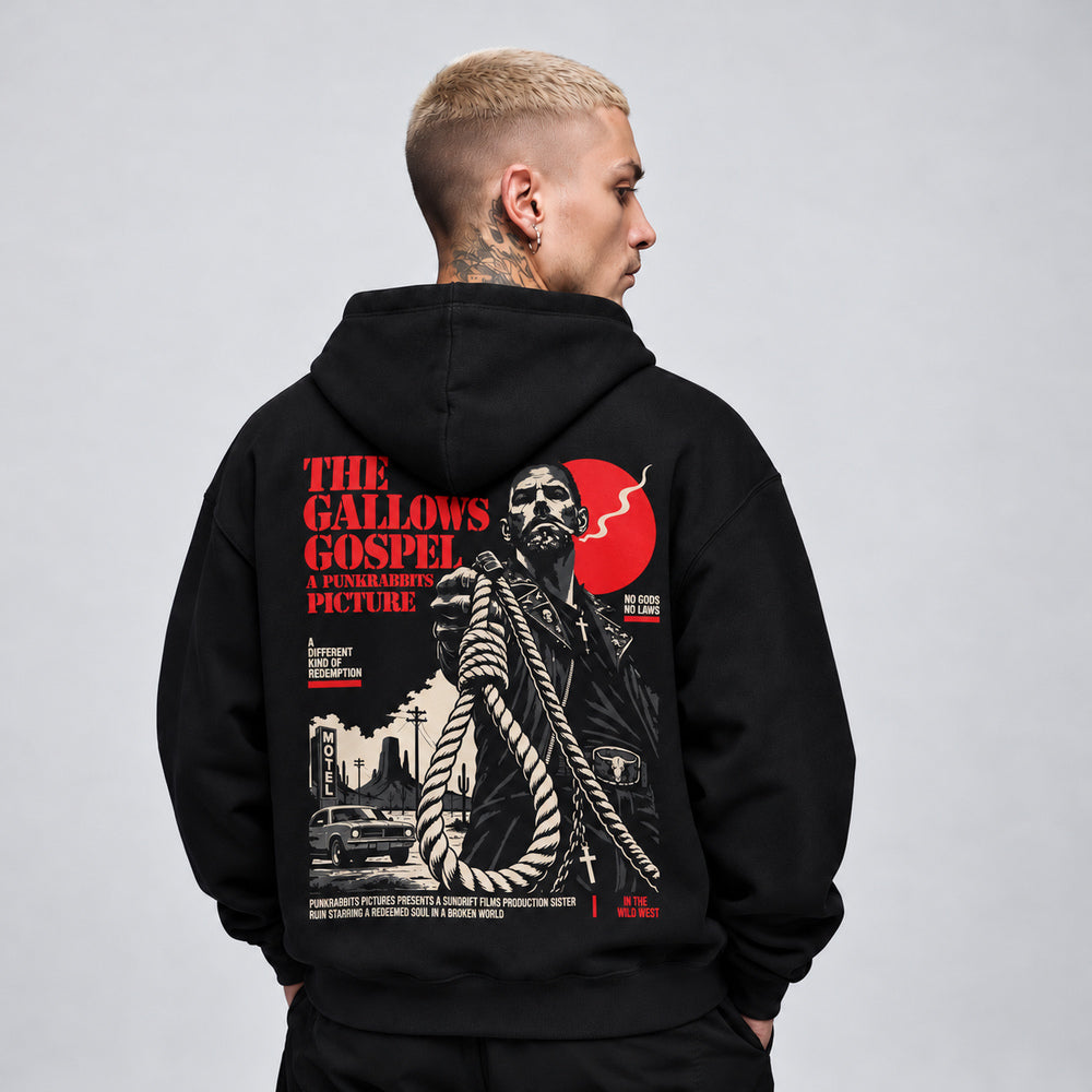James wearing The Gallows Gospel black Gildan 18500 hoodie, back view with noose-bearing outlaw, desert motel and red disc