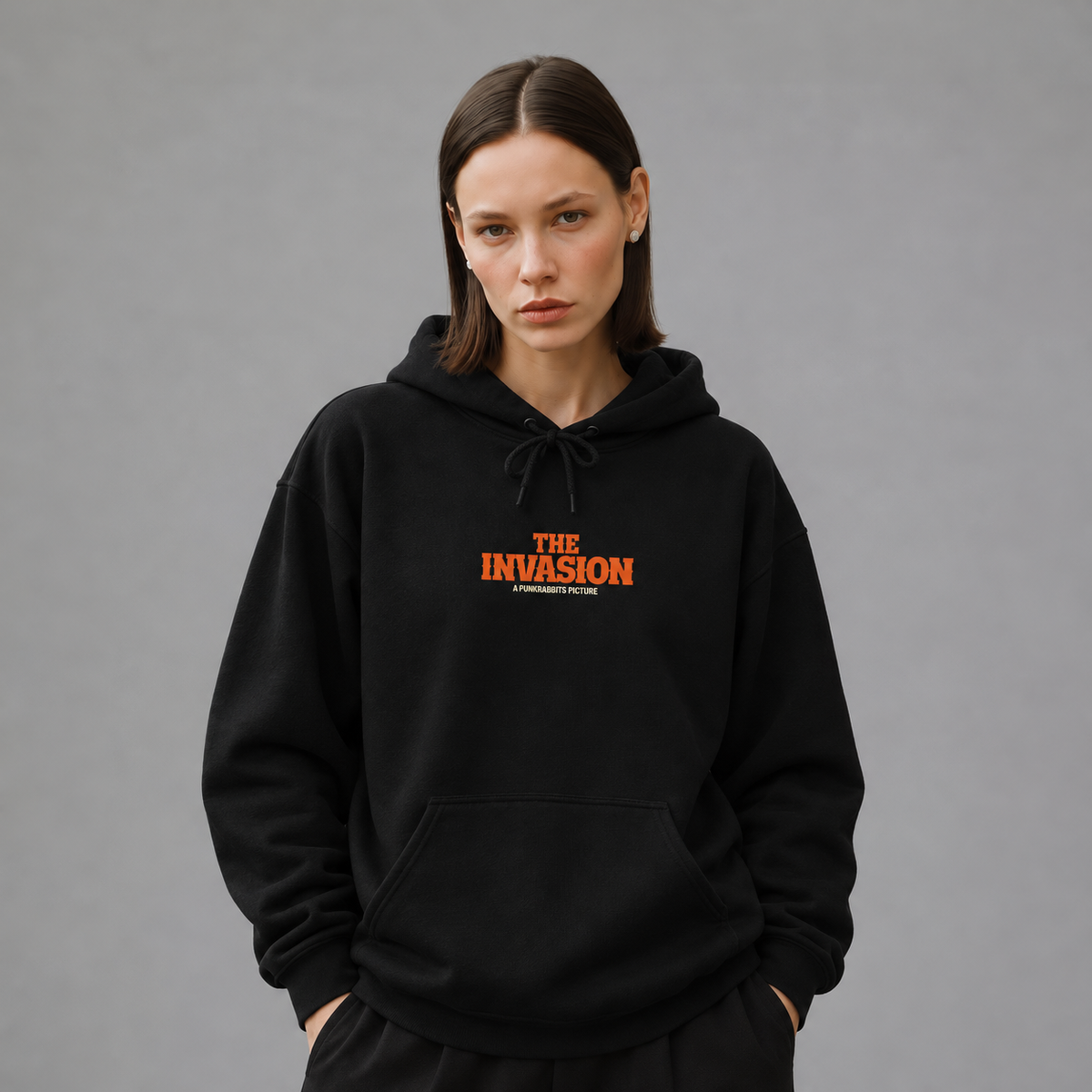 Mara wearing The Invasion black hoodie, front view — styled mockup